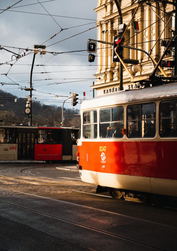 Rote Straßenbahn in Prag an einer Kreuzung, historische Gebäude und Oberleitungen